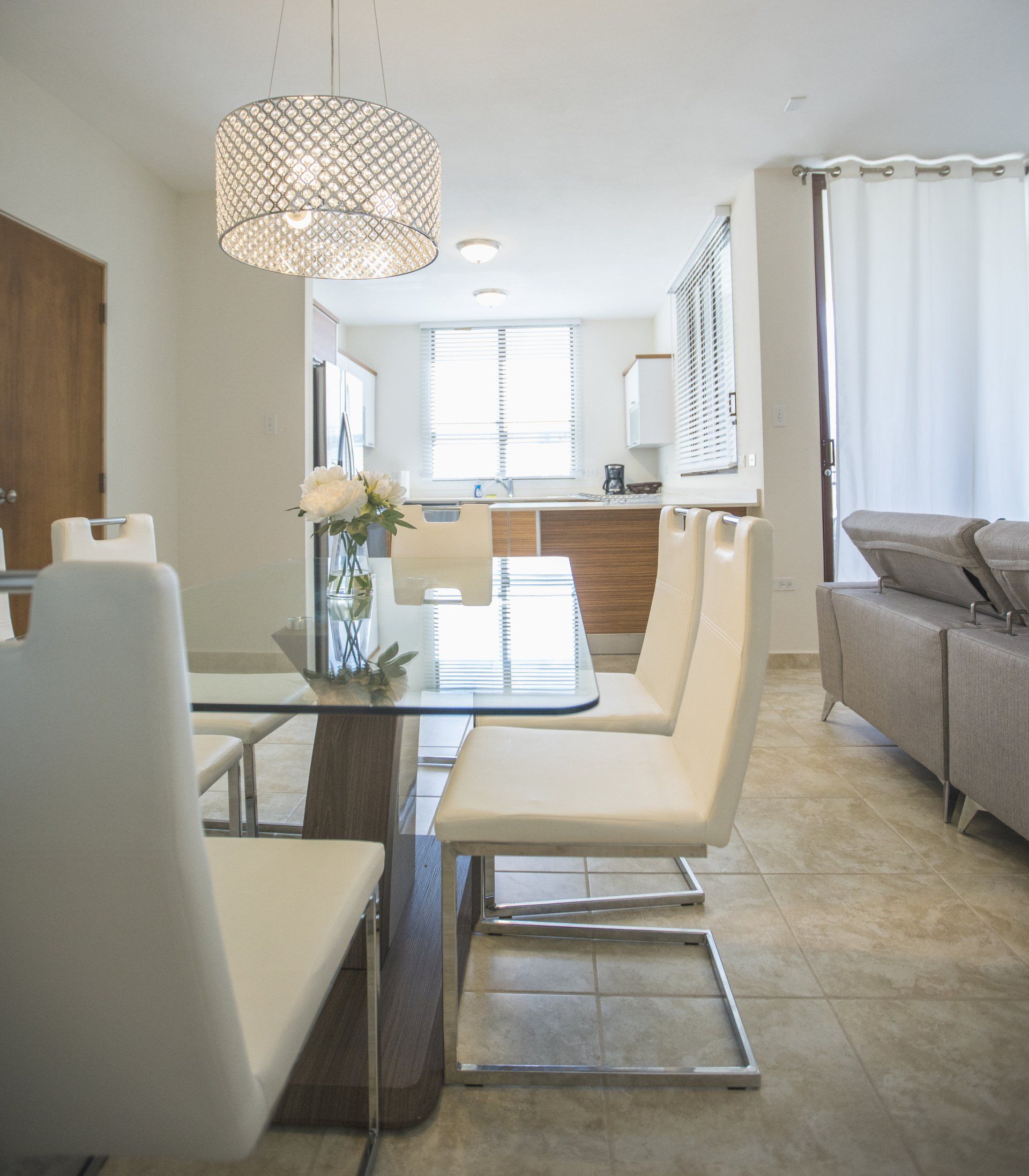 A dining room with white chairs and a glass table