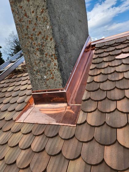 Solins de cheminée rouillés sur un toit de bardeaux sous un ciel bleu