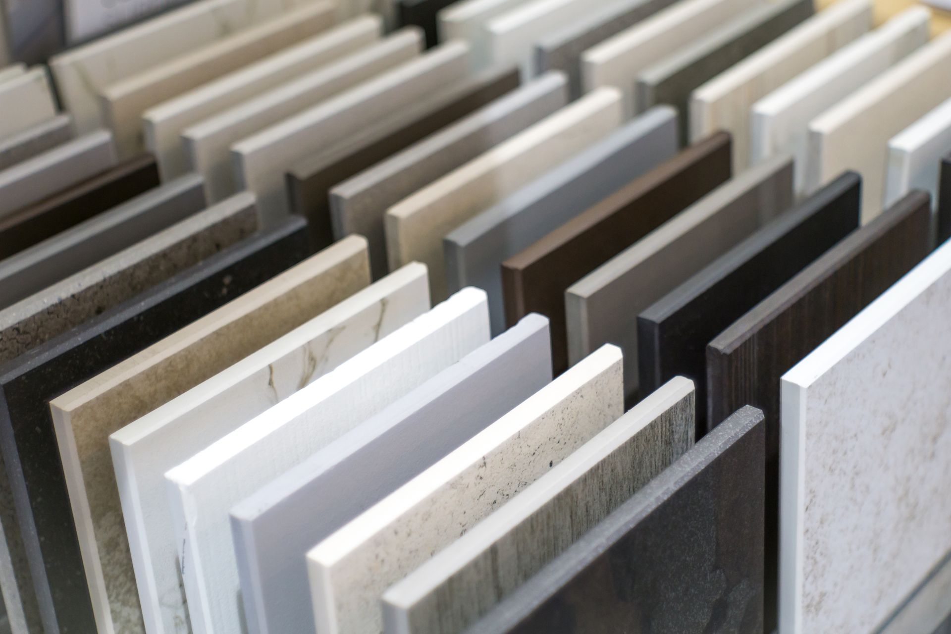 Des rangées d'échantillons de pierres ou de carreaux assortis, présentés verticalement dans une salle d'exposition.