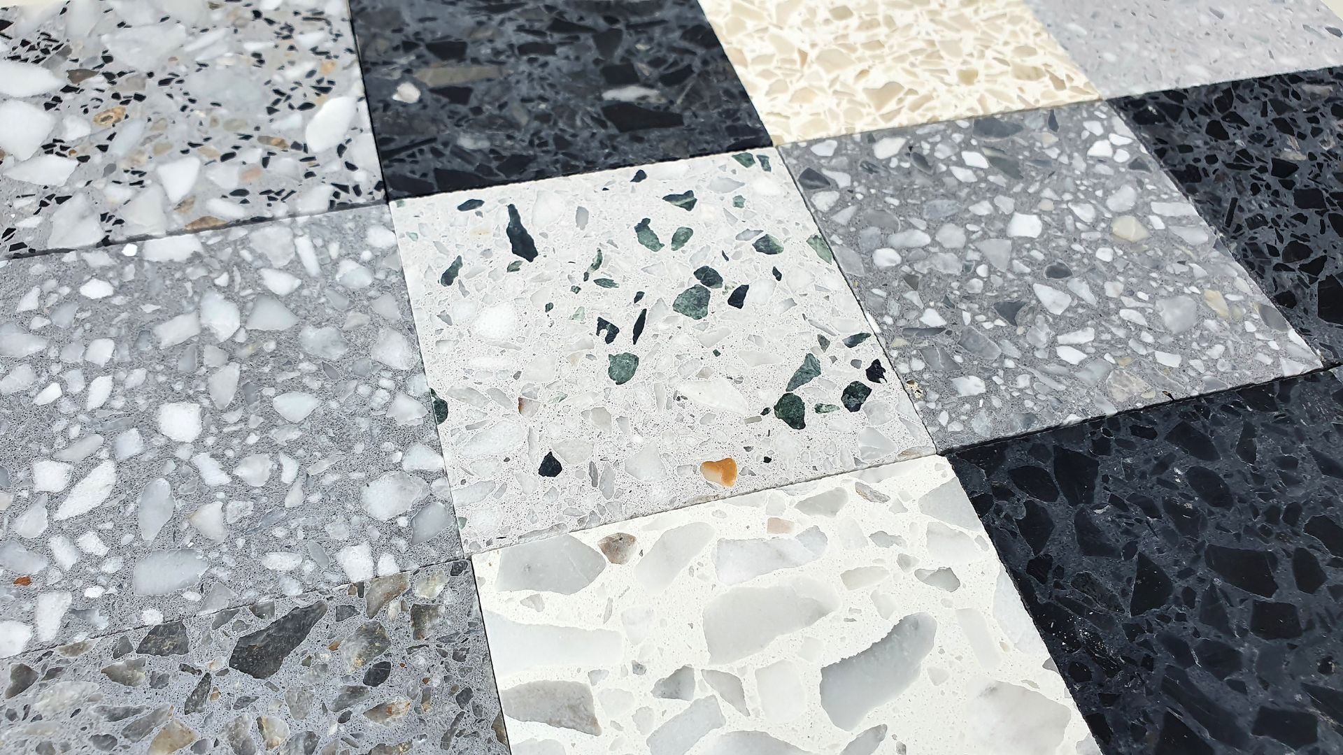 Carrelage de sol en terrazzo à damier blanc, gris, noir et blanc cassé.