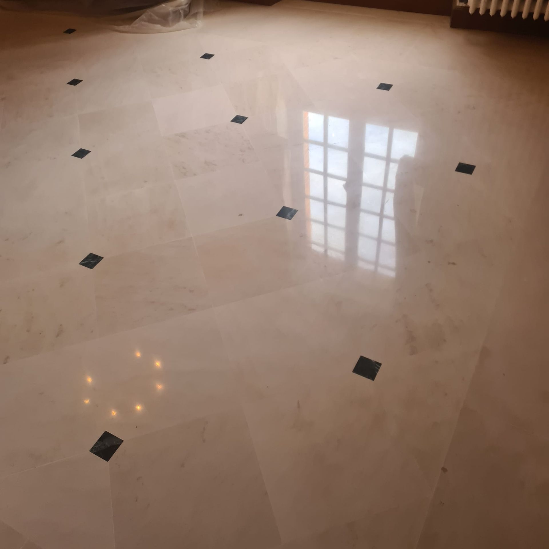 Couloir carrelé avec un fauteuil en cuir marron et une petite table sur la droite, menant à une porte lumineuse.