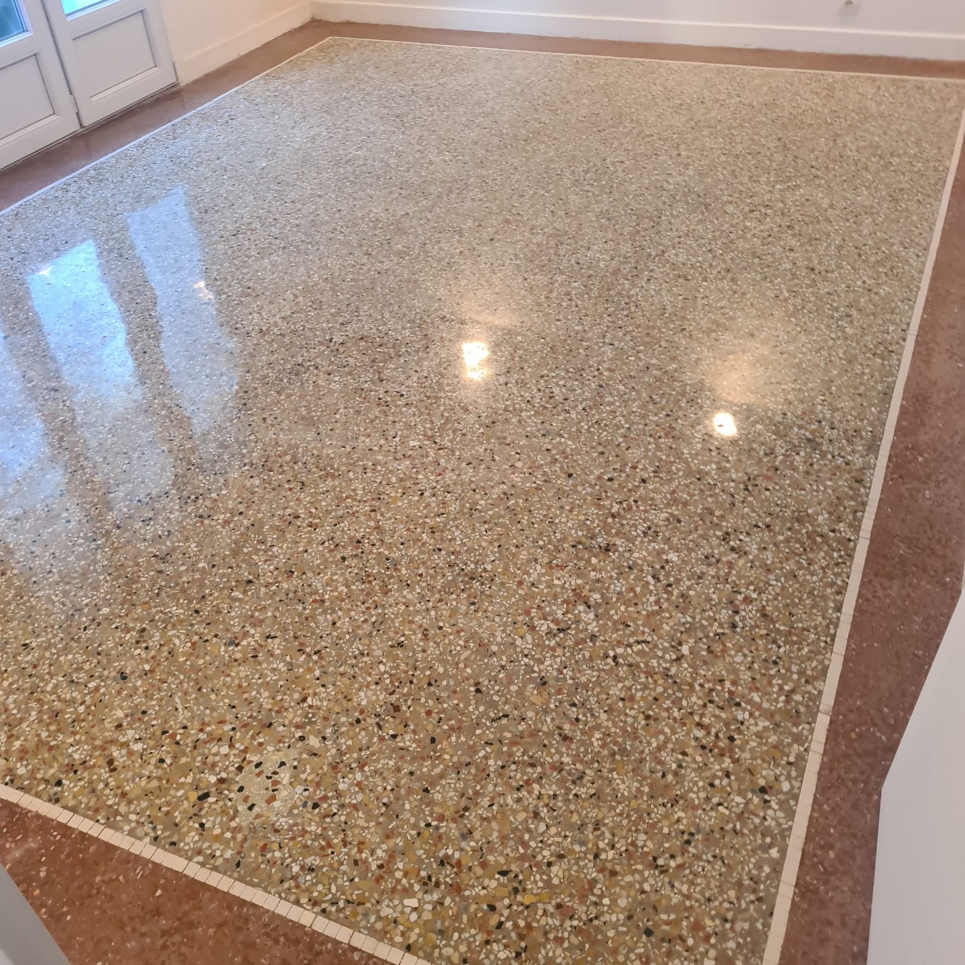 Sol en terrazzo brillant moucheté avec une bordure blanche dans une pièce vide