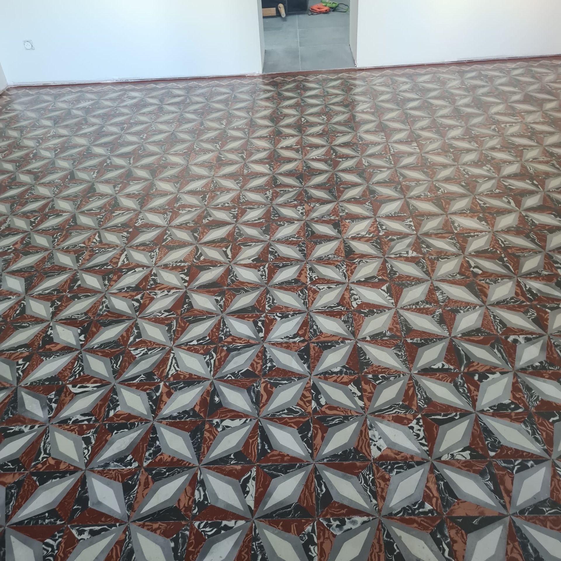 Sol carrelé à motifs dans une pièce intérieure vide, près d'une porte.
