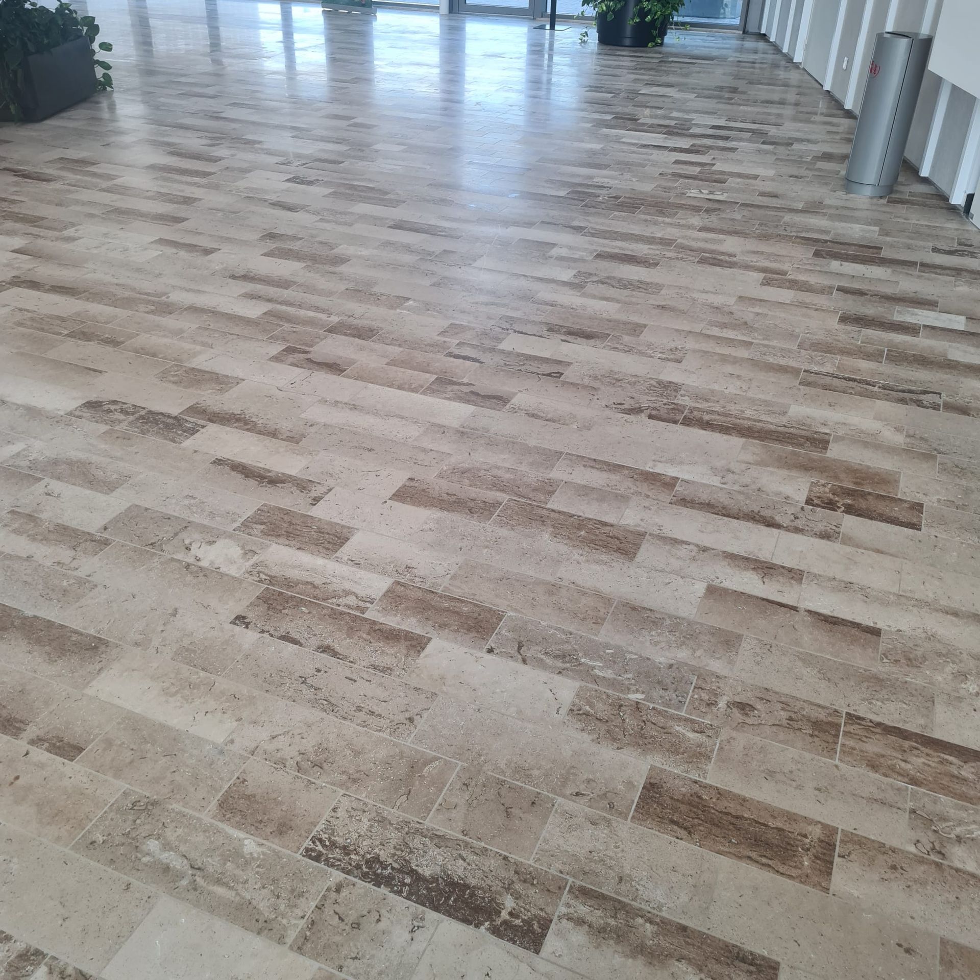Sol carrelé vide dans un couloir intérieur lumineux avec de grandes fenêtres et des colonnes