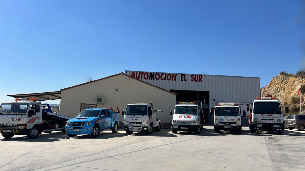 Fila de grúas y un coche azul estacionado afuera del edificio