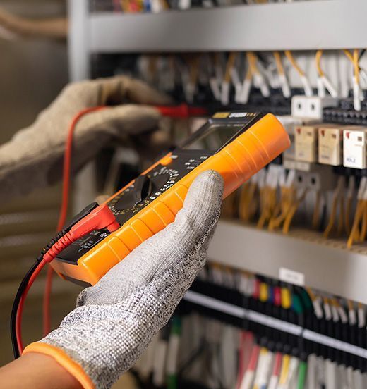 Eine Person hält ein digitales Multimeter in der Hand.