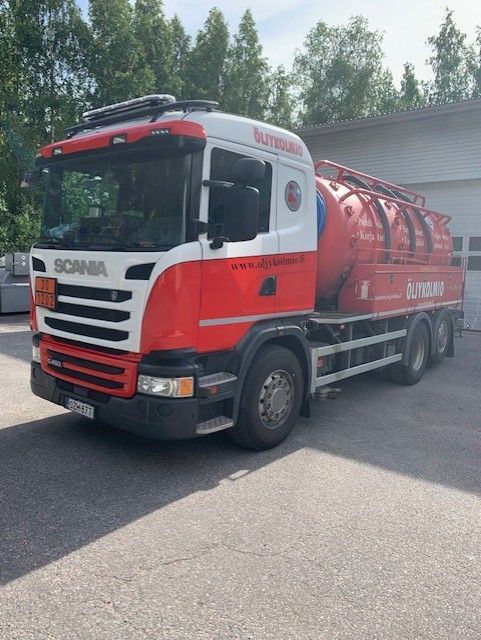 Punavalkoinen Scania-säiliöauto pysäköitynä tien varteen puita taustalla
