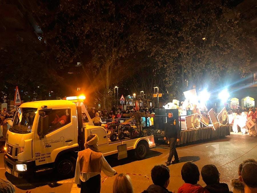 Una grúa y la gente se reunieron en un evento callejero nocturno brillantemente iluminado con luces intermitentes.