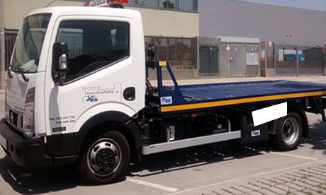 Grúa de plataforma blanca estacionada en una calle, vista lateral con detalles azules y amarillos.