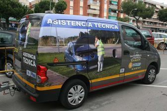 Van de asistencia técnica gris con gráficos de un mecánico y un coche en la carretera