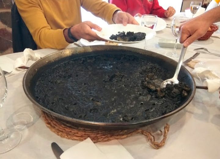 Una olla de arroz negro con una cuchara dentro