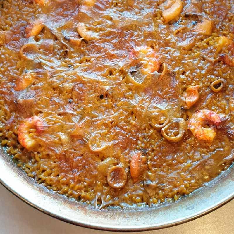 Un primer plano de una sartén de arroz con camarones y cebollas.