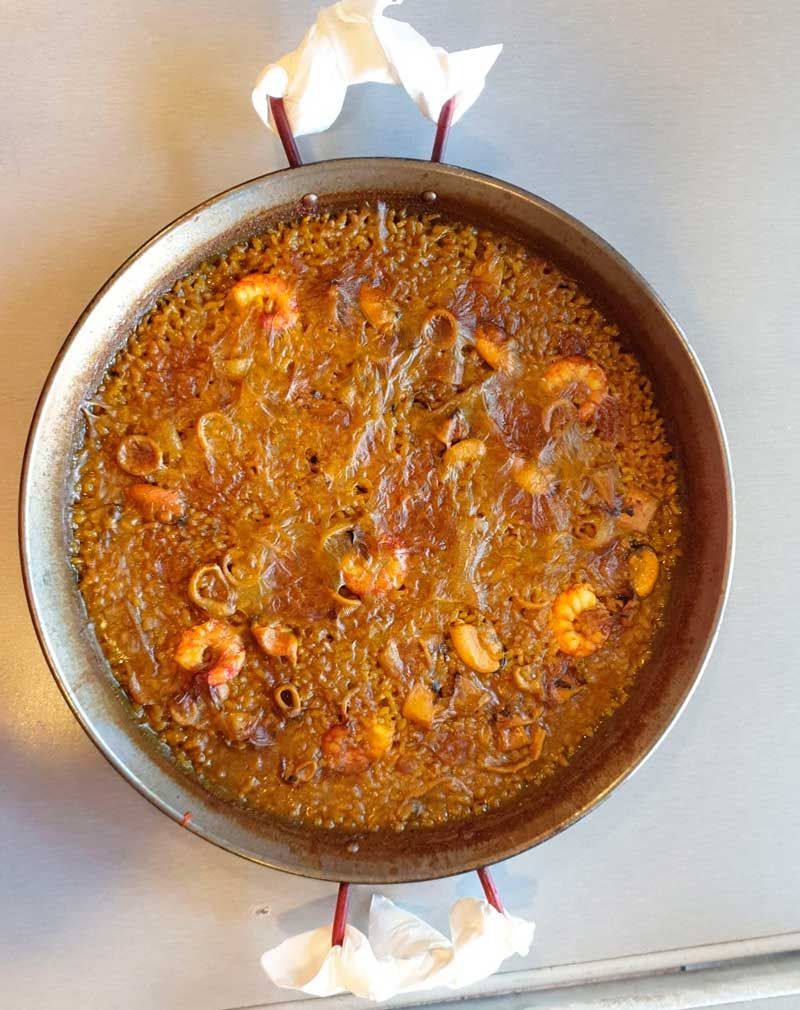 Una sartén llena de arroz y camarones sobre una mesa.
