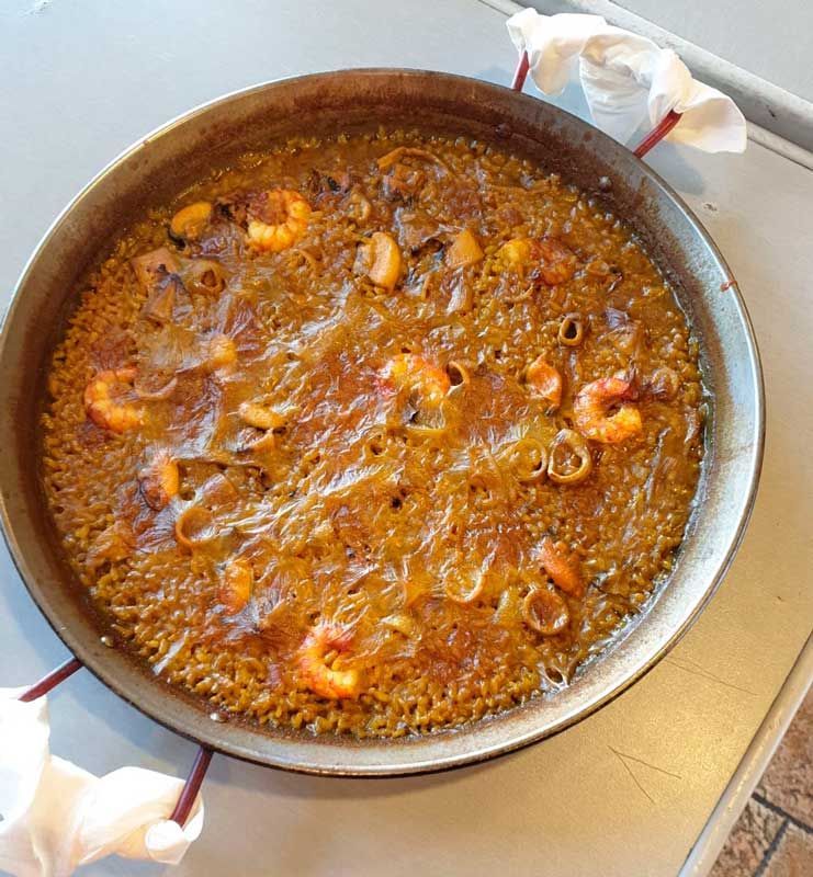 Una sartén llena de arroz y camarones sobre una mesa.