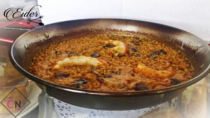 Una sartén llena de arroz y camarones está sobre una mesa.