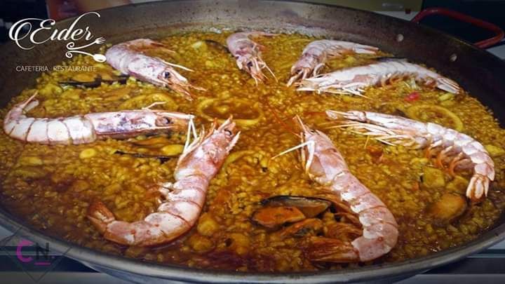 En una sartén se está cocinando una paella con camarones y mejillones.