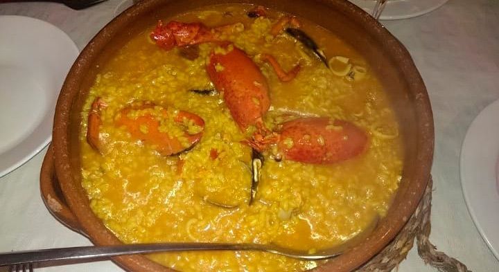 Un recipiente con comida y una cuchara dentro está sobre una mesa.