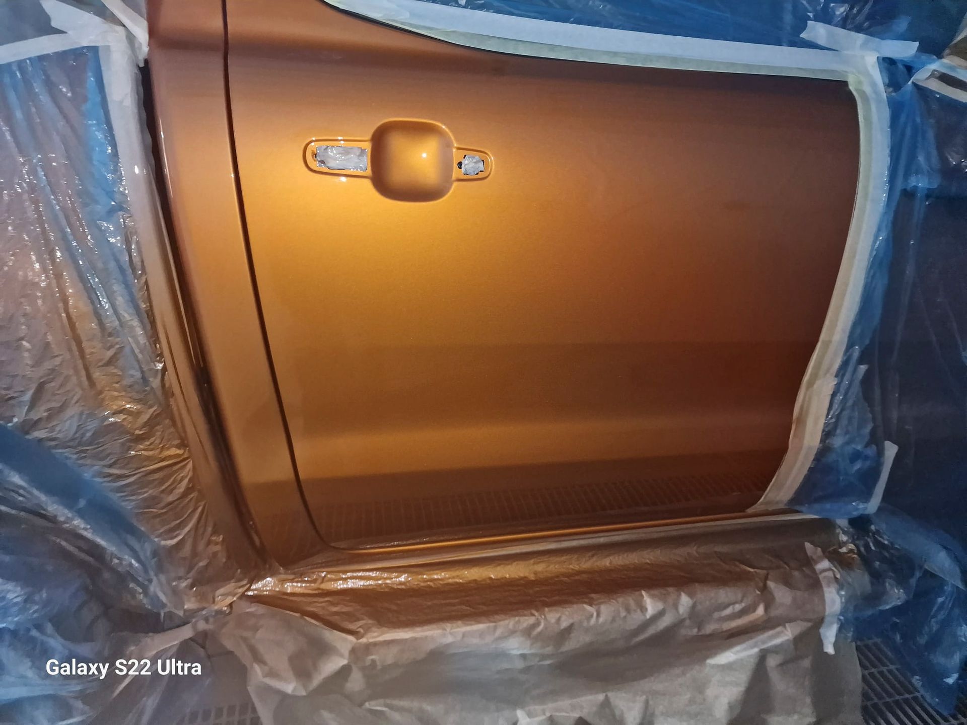 Eine Autotür wird mit Plastik verkleidet und lackiert.