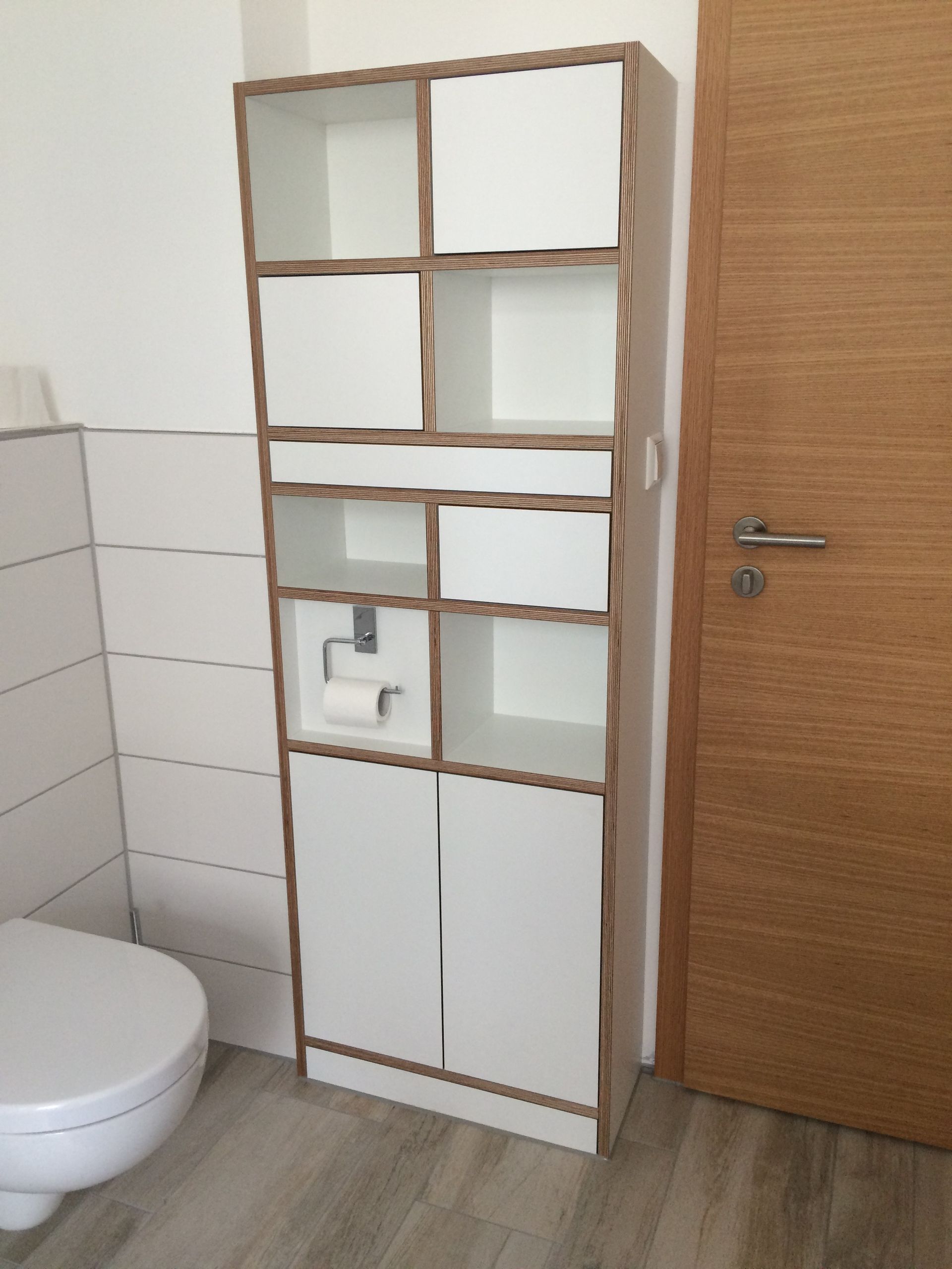 Ein Badezimmer mit einer Toilette, einem Regal und einer Tür