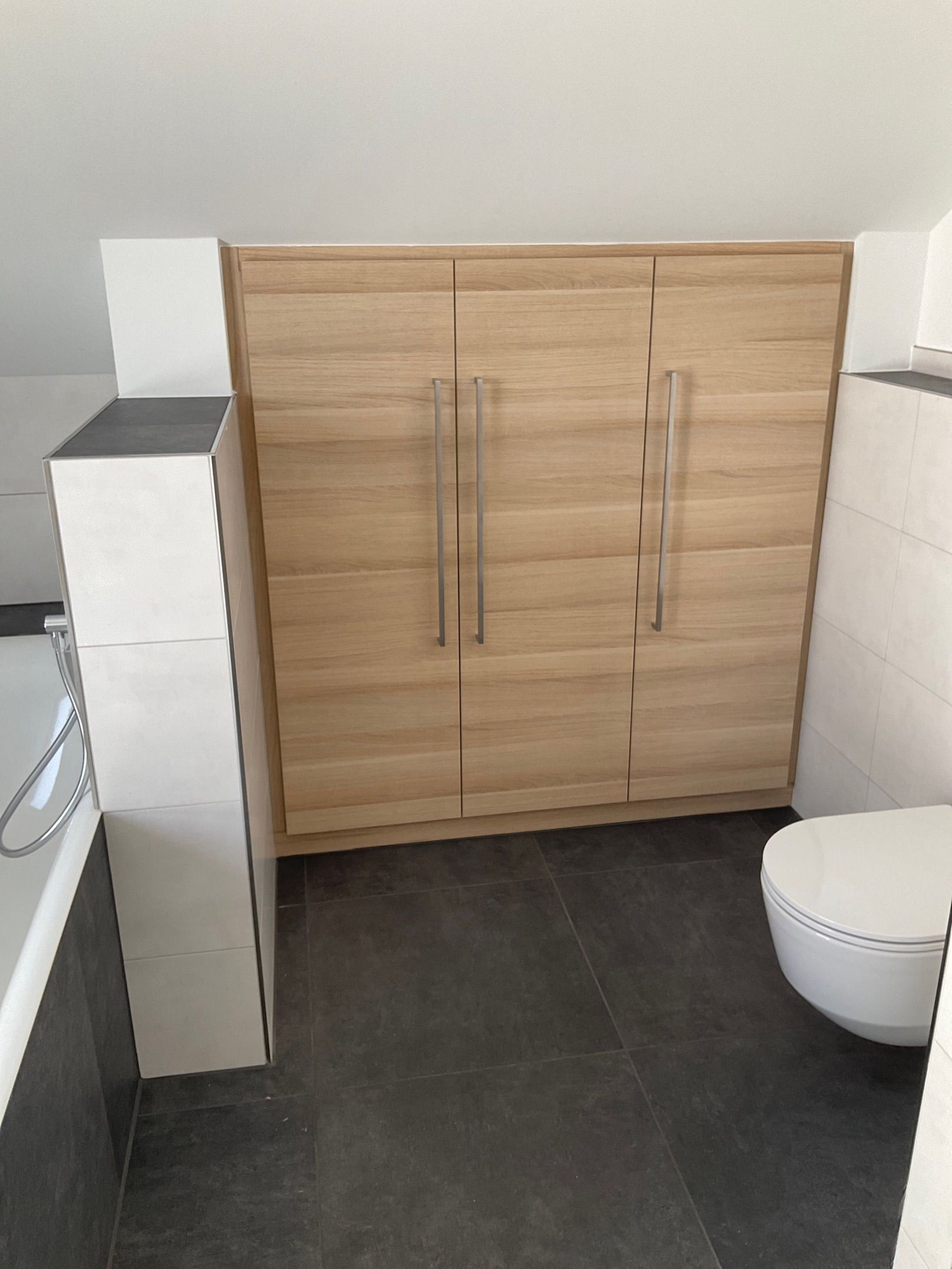 Ein Badezimmer mit Toilette und Holzschrank