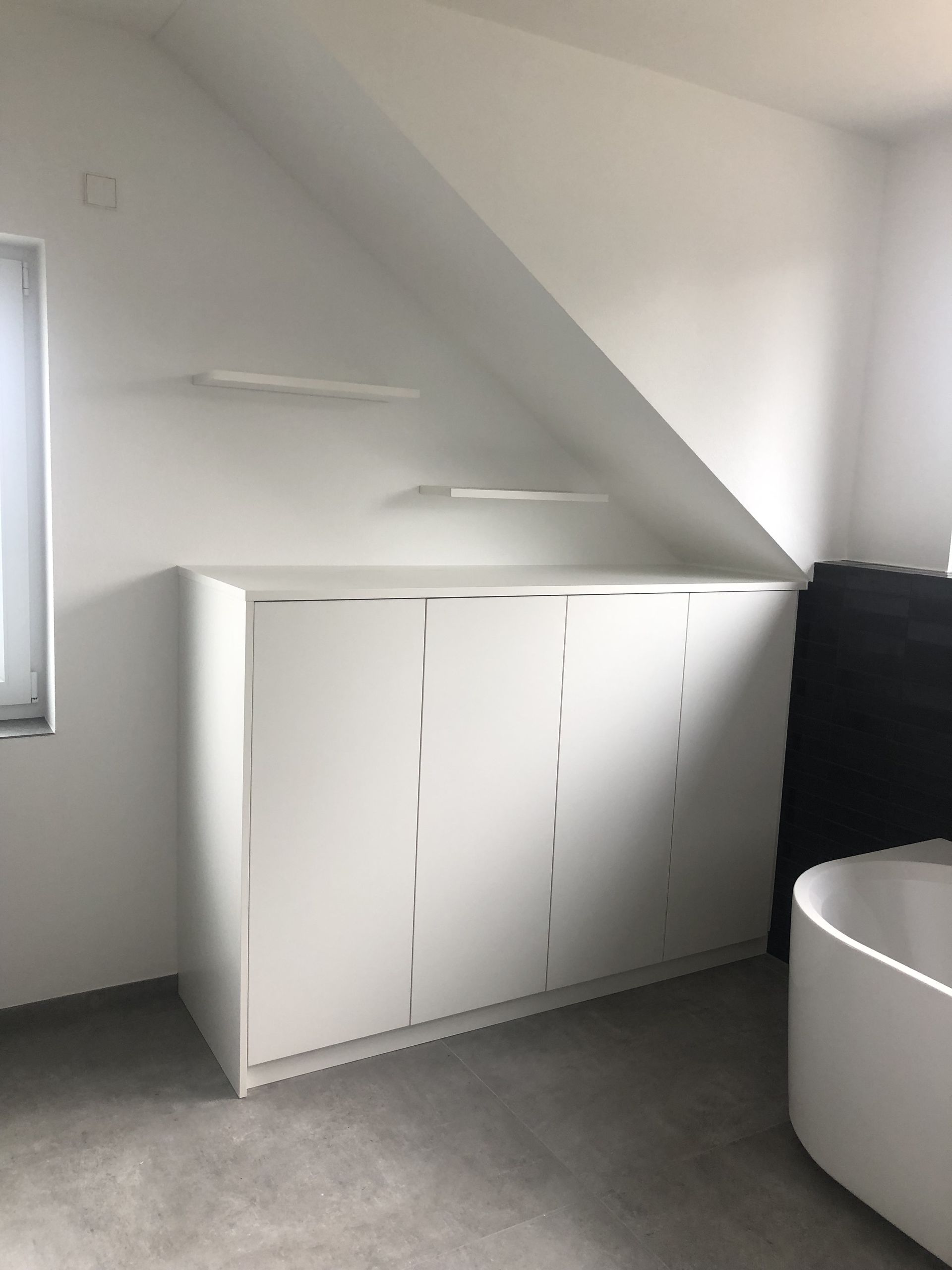 Ein Badezimmer mit weißen Schränken und einer Badewanne