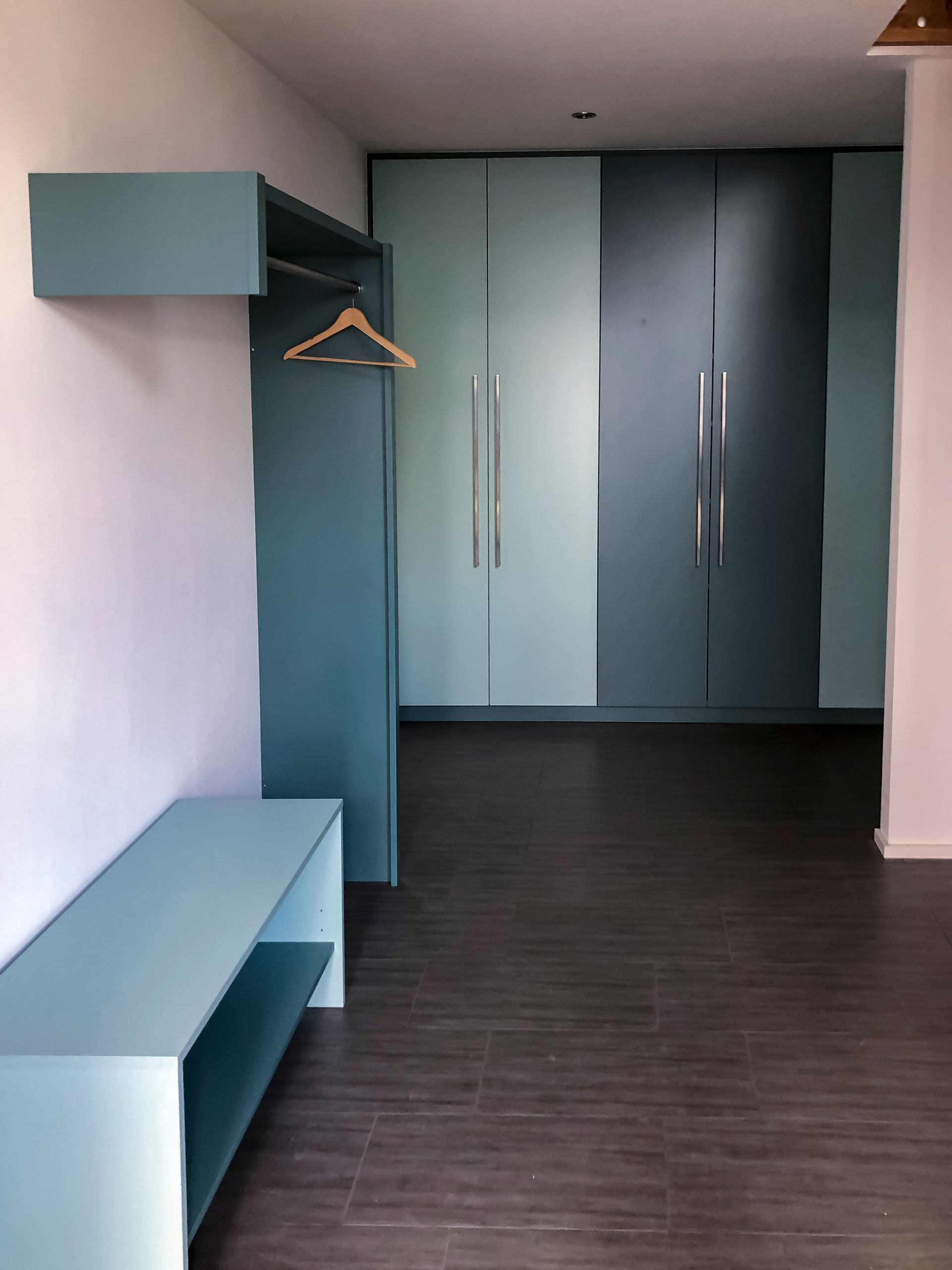 Ein Zimmer mit einem Regal und einem Kleiderbügel an der Wand