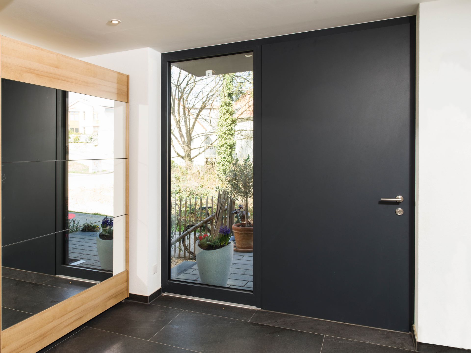 Ein Flur mit einer schwarzen Tür und einem Spiegel.