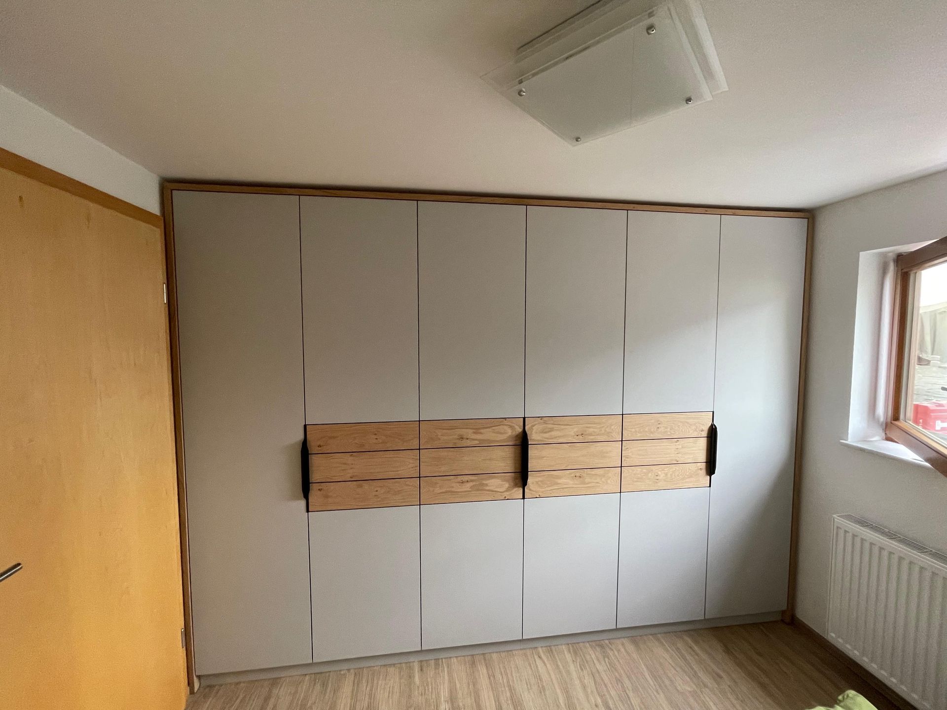 Ein Schlafzimmer mit großem Kleiderschrank und Fenster.