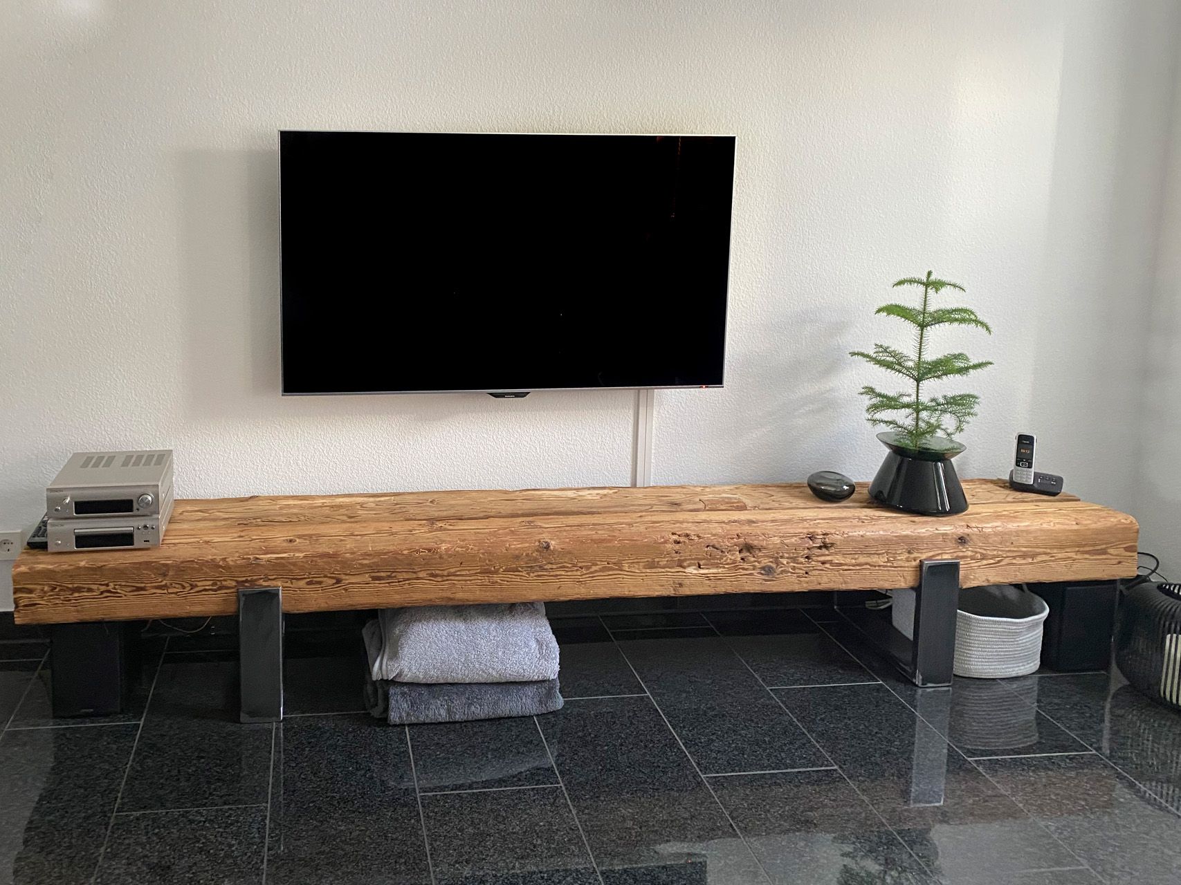Ein Flachbildfernseher ist an der Wand über einem Entertainment-Center aus Holz montiert.