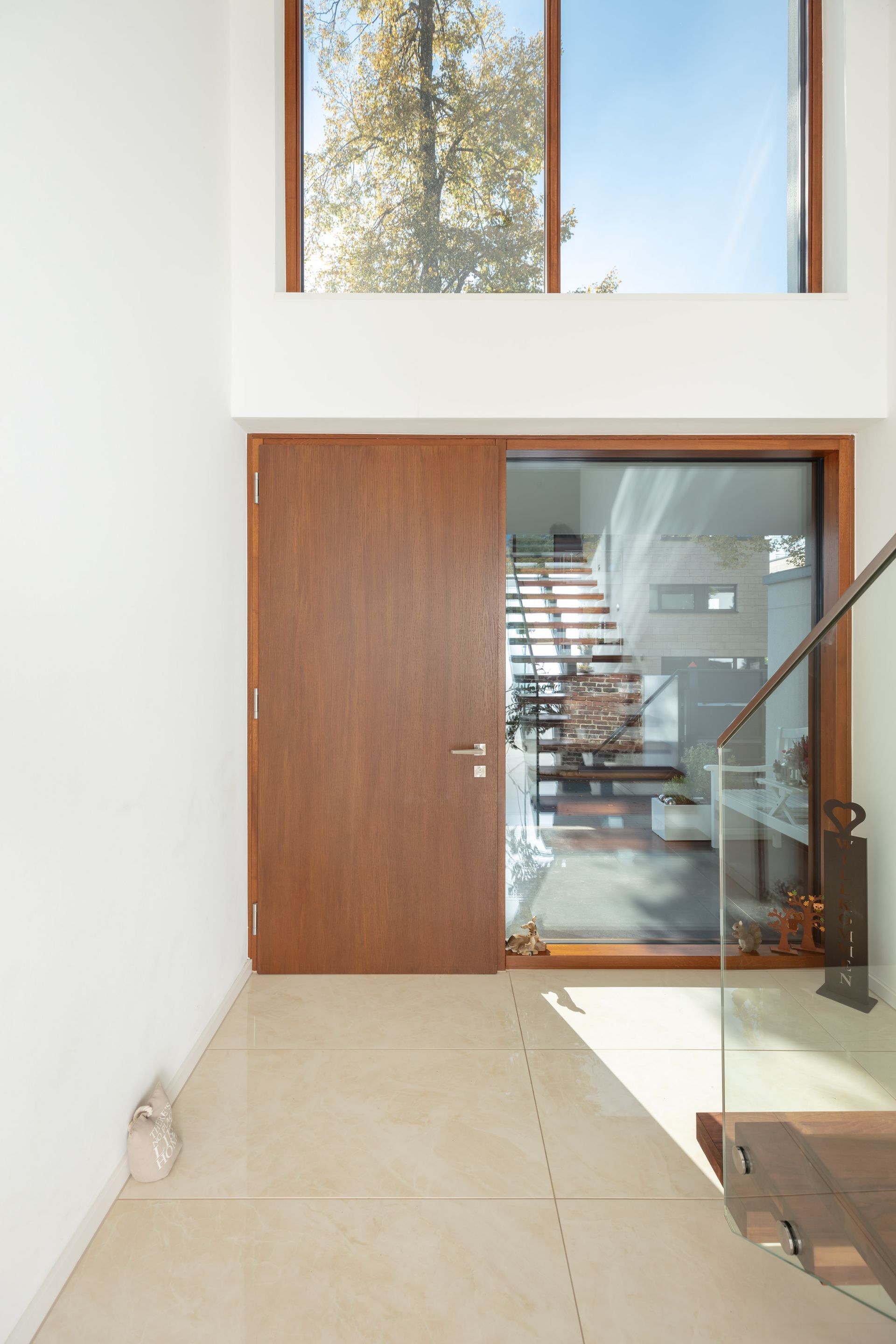 Ein Flur mit einer Holztür und einer Glastreppe