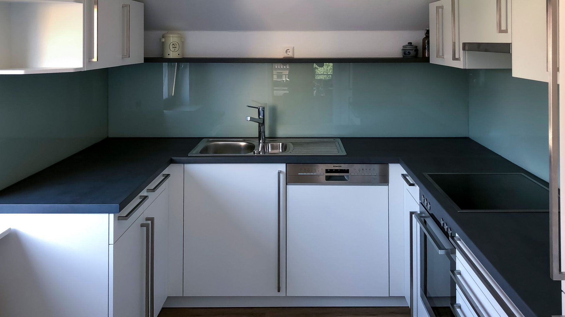 Eine Küche mit weißen Schränken und schwarzen Arbeitsplatten