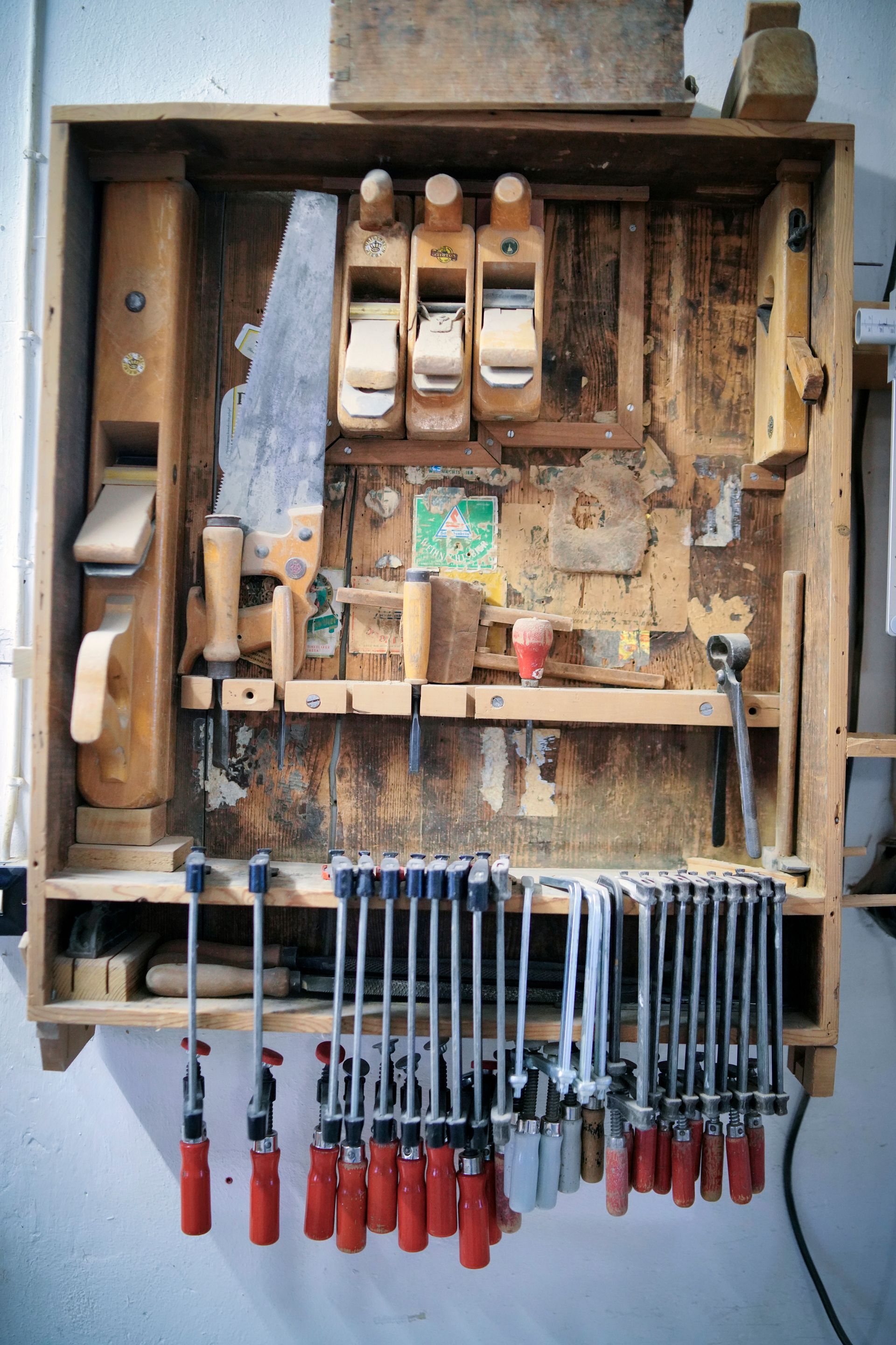 Ein Haufen Holzbearbeitungswerkzeuge, die an einer Wand hängen