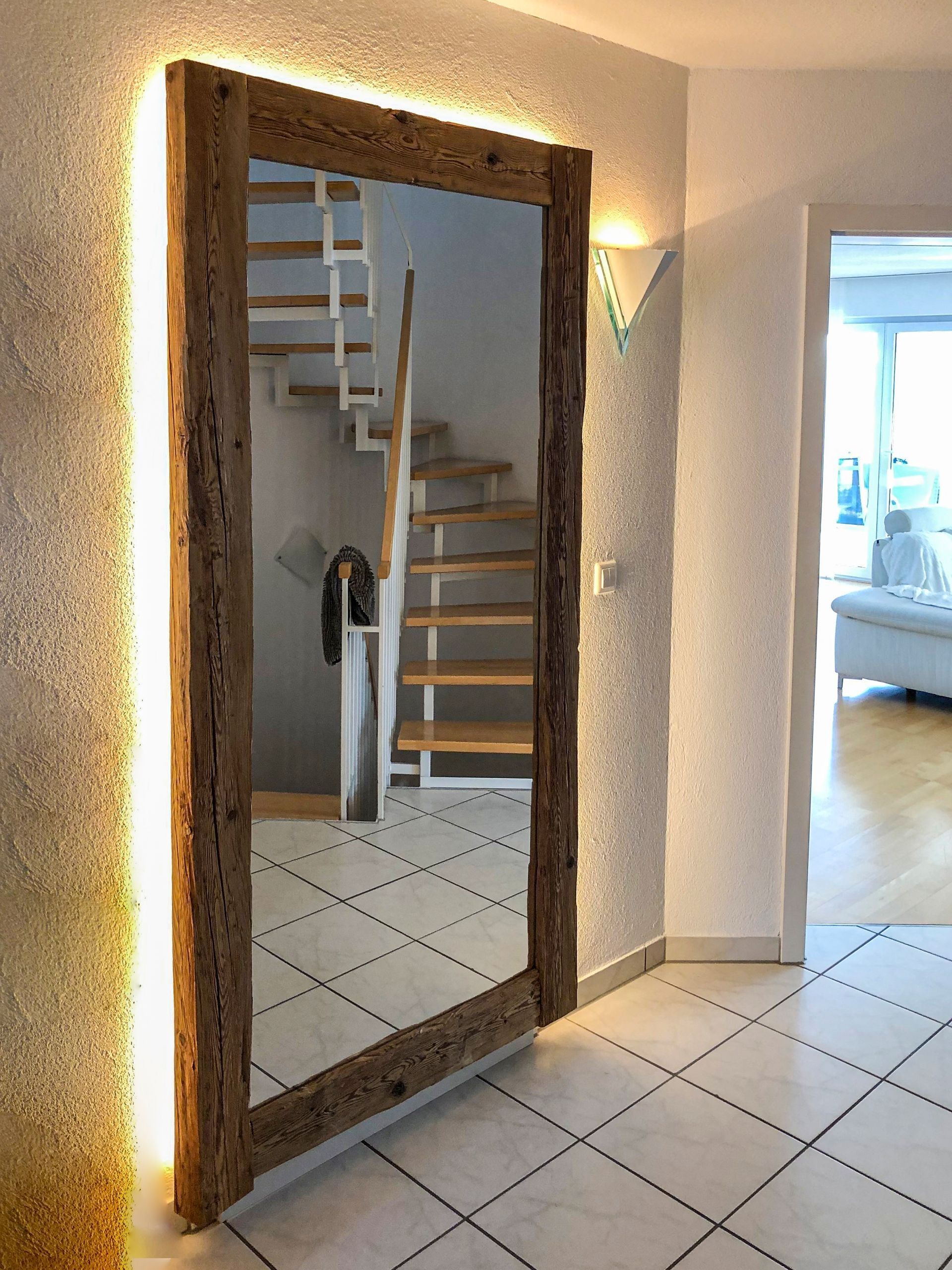 Ein Ganzkörperspiegel in einem Flur mit Treppen im Hintergrund