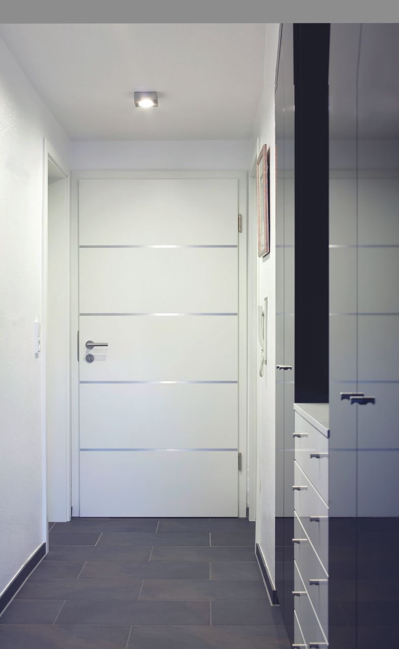 Ein Flur mit einer weißen Tür und einem Spiegel an der Wand.