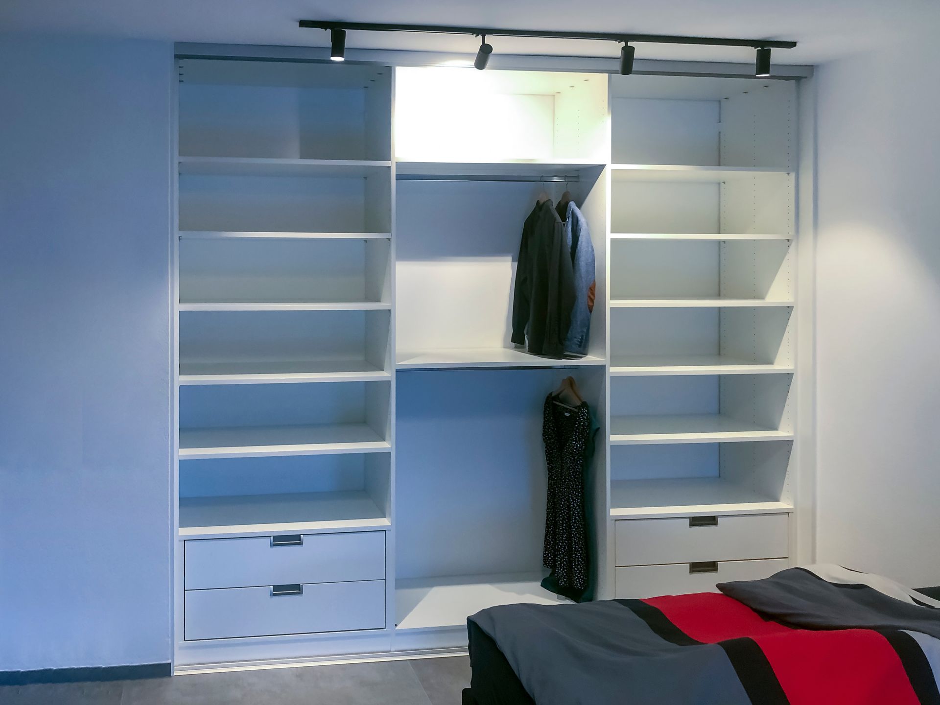 Ein Schlafzimmer mit vielen Regalen und Schubladen und einem Bett