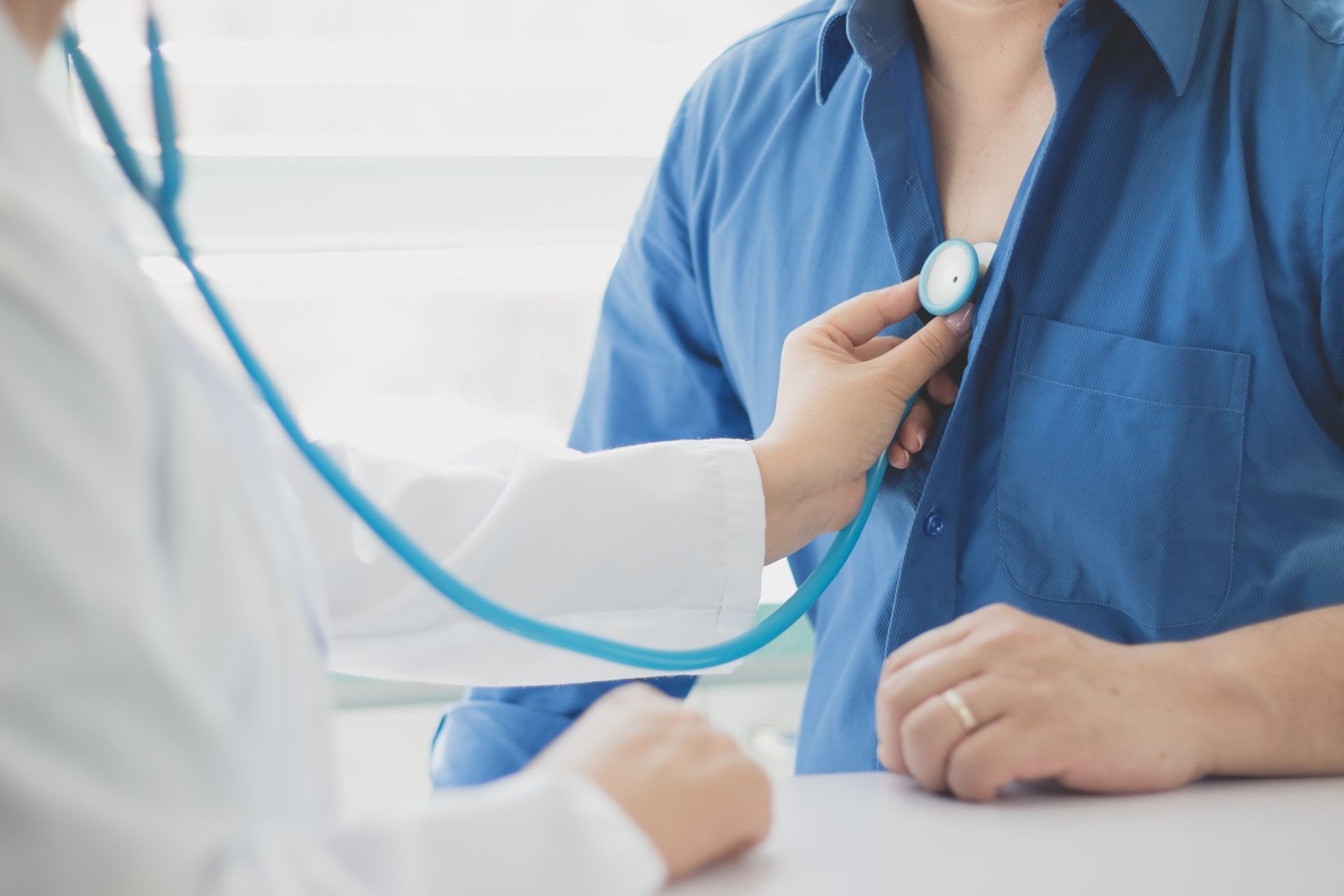 Ein Arzt führt eine Ultraschalluntersuchung des Brustkorbs eines Patienten durch. Beide tragen Masken.