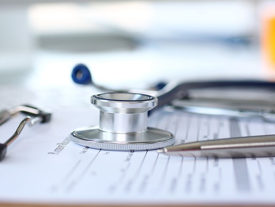 Silbernes Stethoskop auf einem Patientenformular mit einem Stift. Medizinische Umgebung.