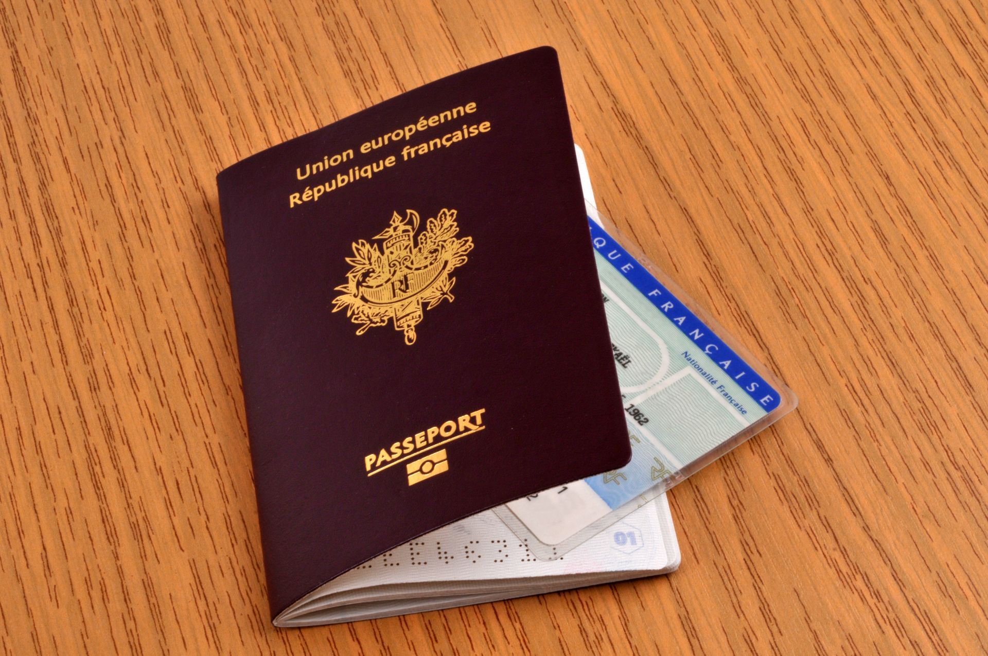 Passeport français ouvert, carte d'identité posée sur une surface en bois.