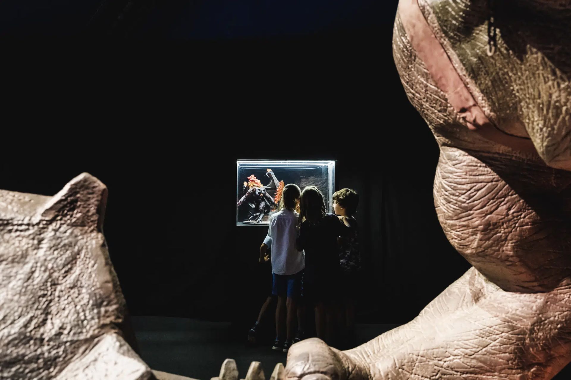 Un grupo de personas está de pie frente a una estatua de un dinosaurio.