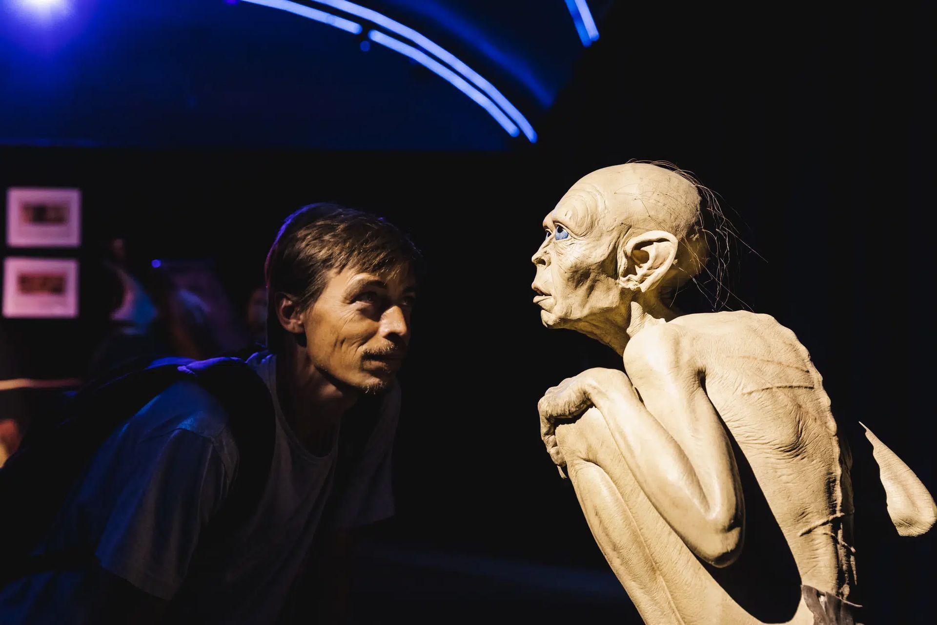 Un hombre mira una estatua de Gollum en una habitación oscura.