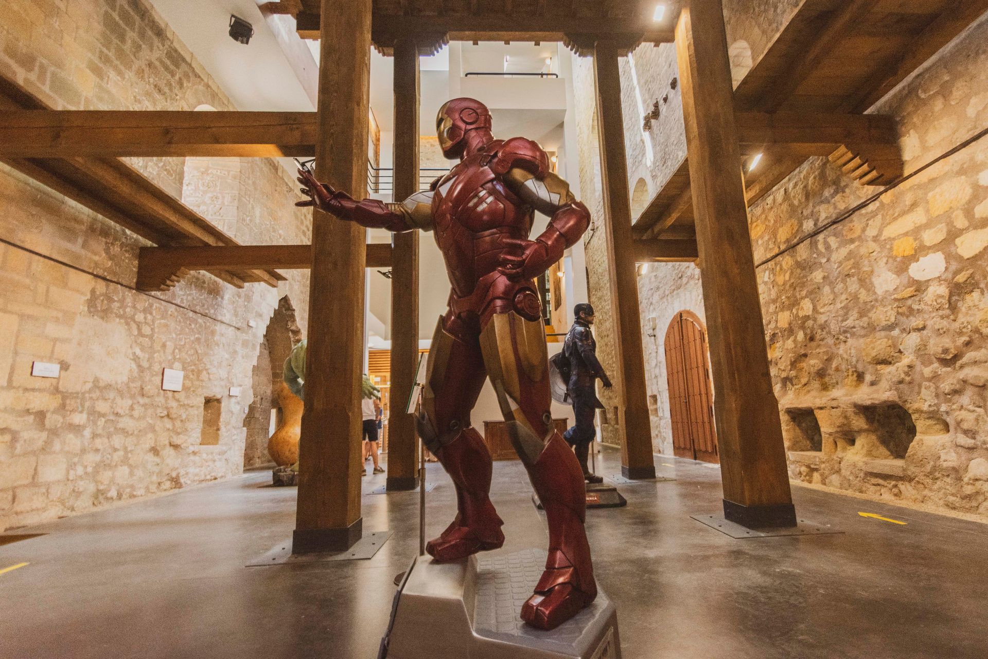 Una estatua de Iron Man está de pie en una habitación rodeada de pilares de madera.
