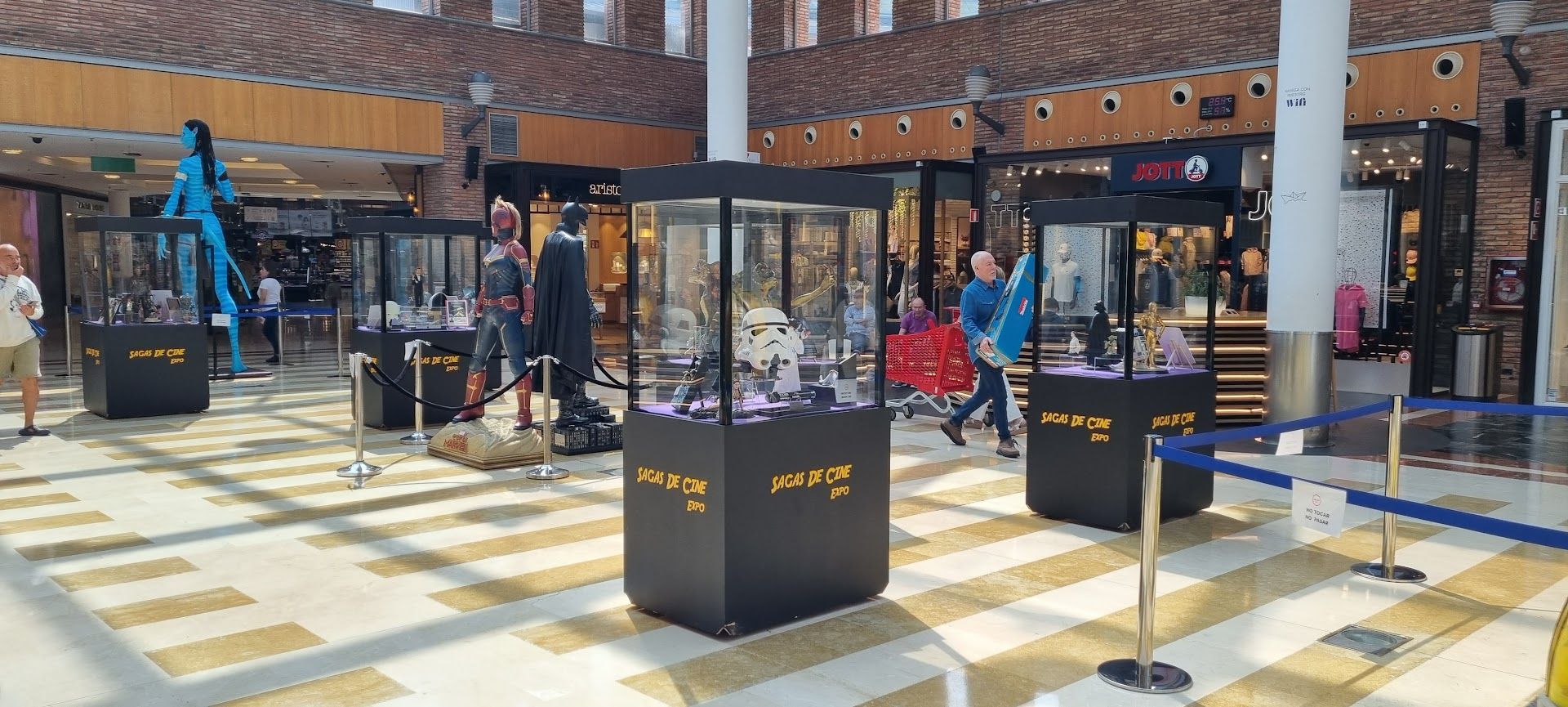 Un grupo de personas se encuentra alrededor de una vitrina en un centro comercial.