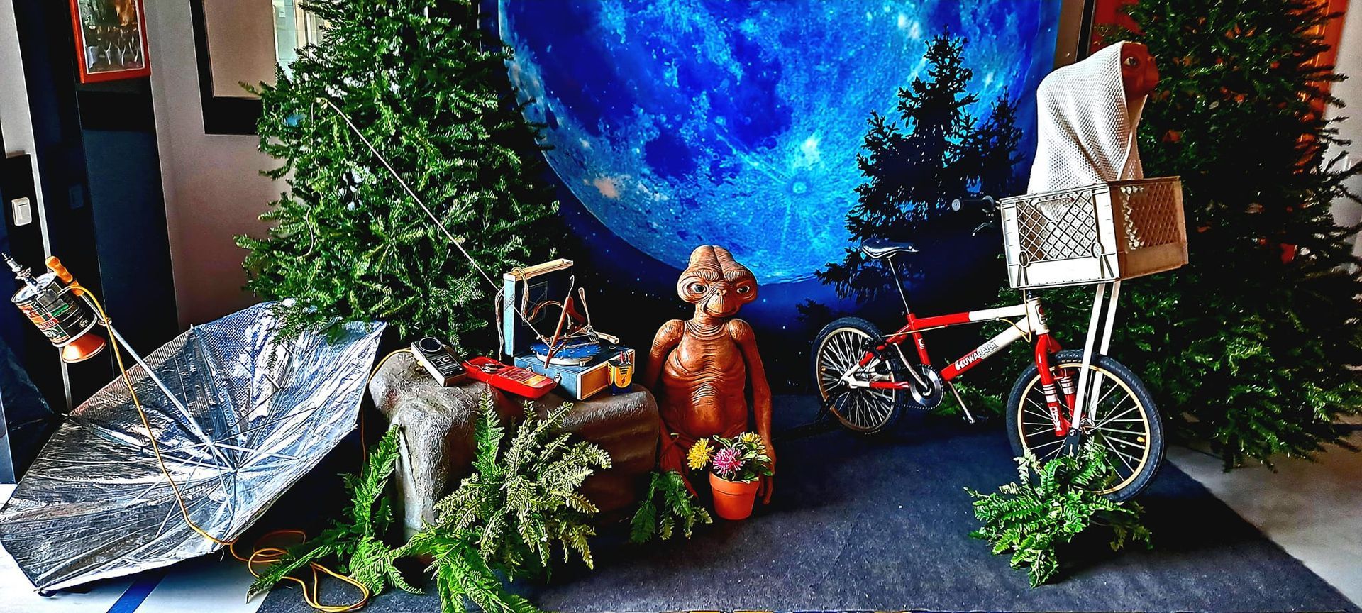 Una habitación con un árbol de Navidad, una bicicleta y una estatua de un extraterrestre.