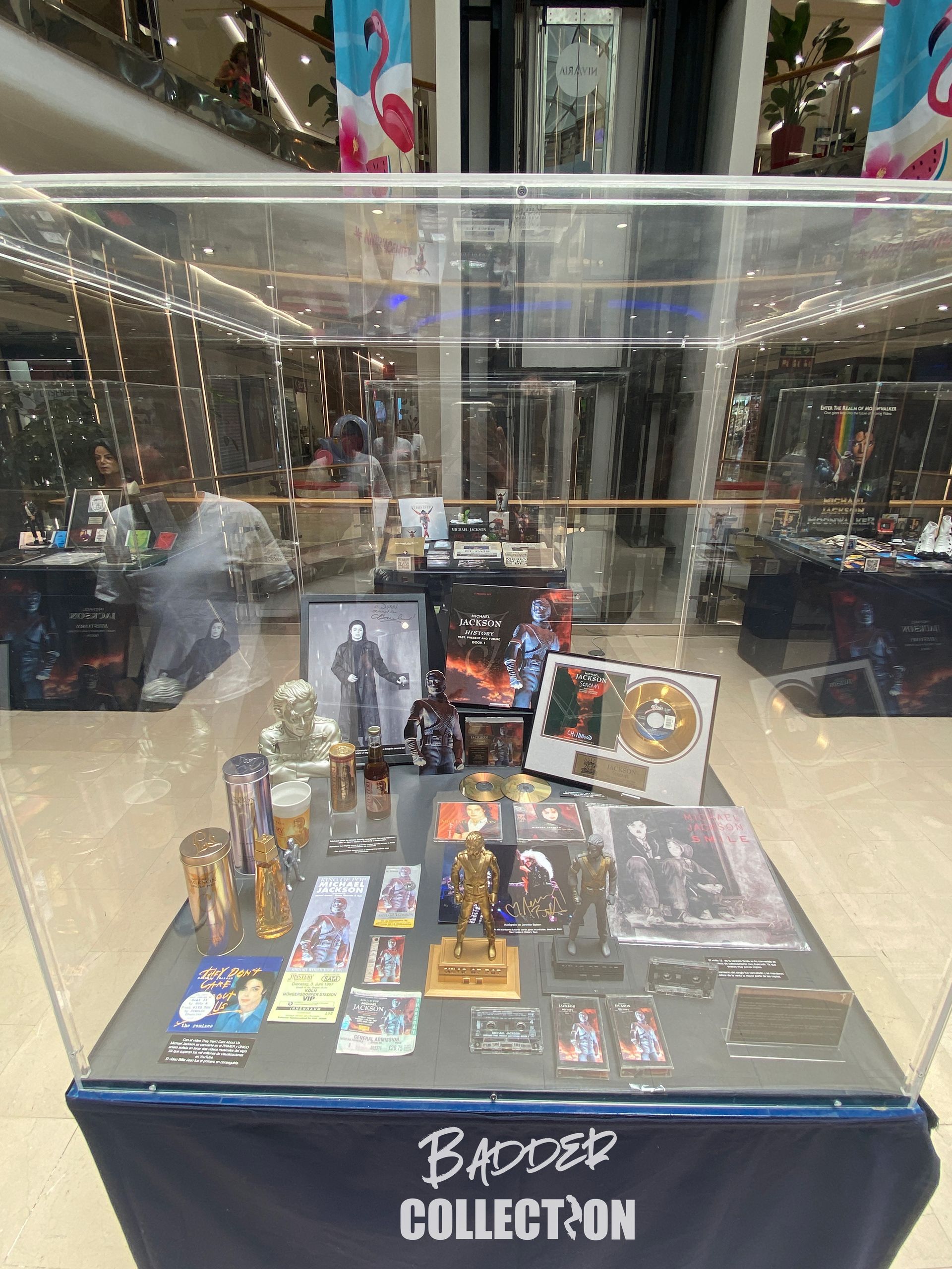 Una mesa con muchos artículos encima, dentro de una vitrina en un centro comercial.