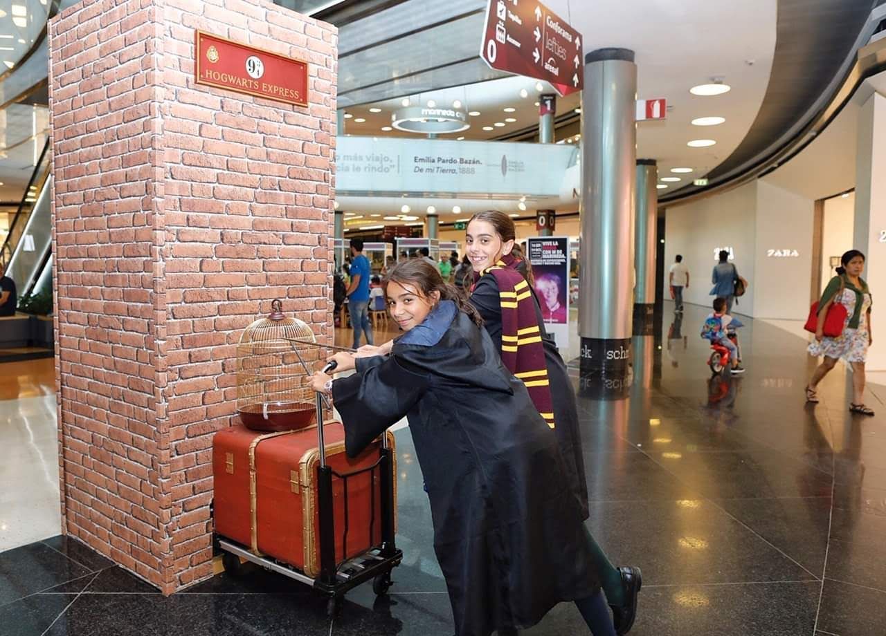 Un niño con un disfraz de Harry Potter está empujando un carrito en un centro comercial.