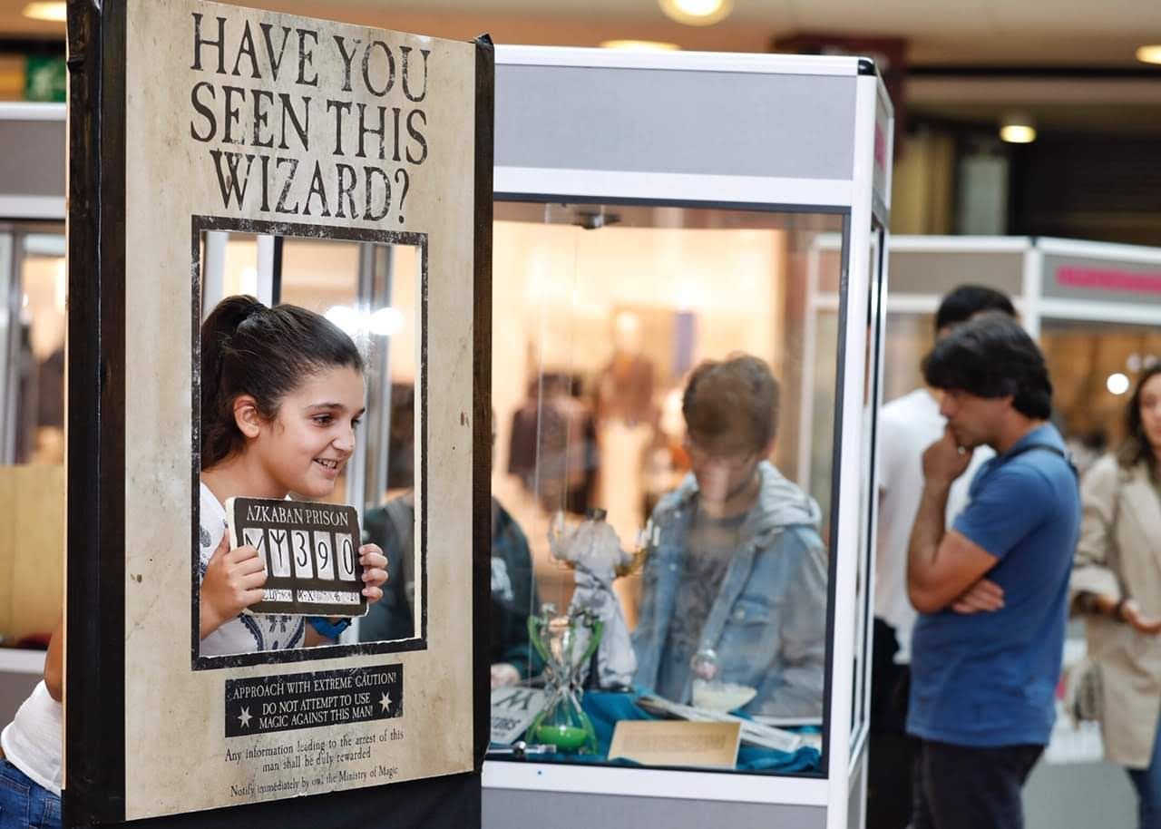 Una mujer está parada frente a un cartel que dice ¿Has visto a este mago?