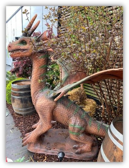 Una estatua de un dragón está sentada junto a barriles.