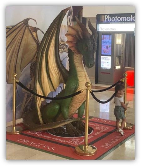 Una estatua de un dragón delante de una máquina fotomática.