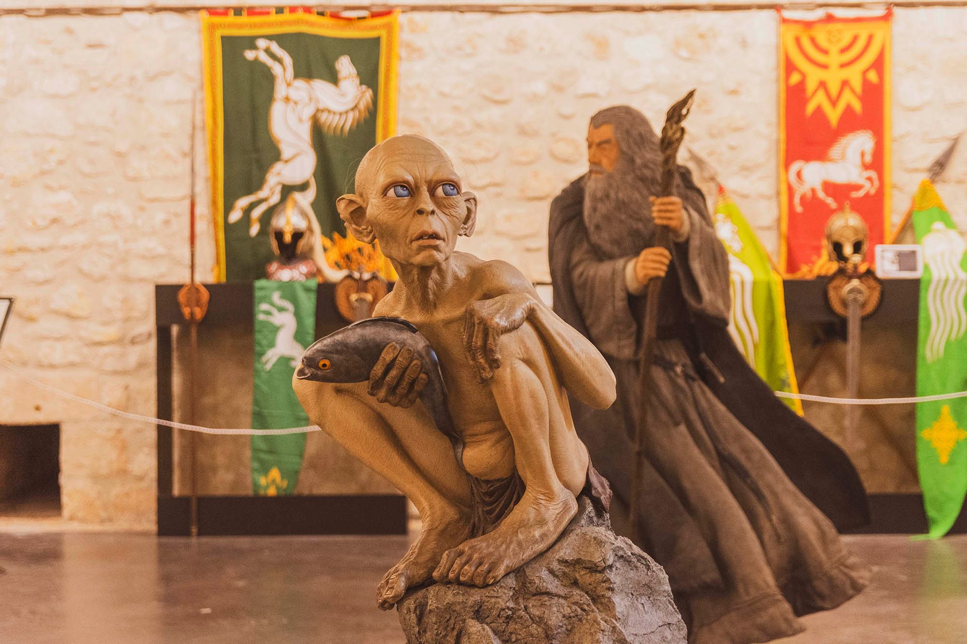 Una estatua de un hombre sosteniendo un pez junto a una estatua de un mago.