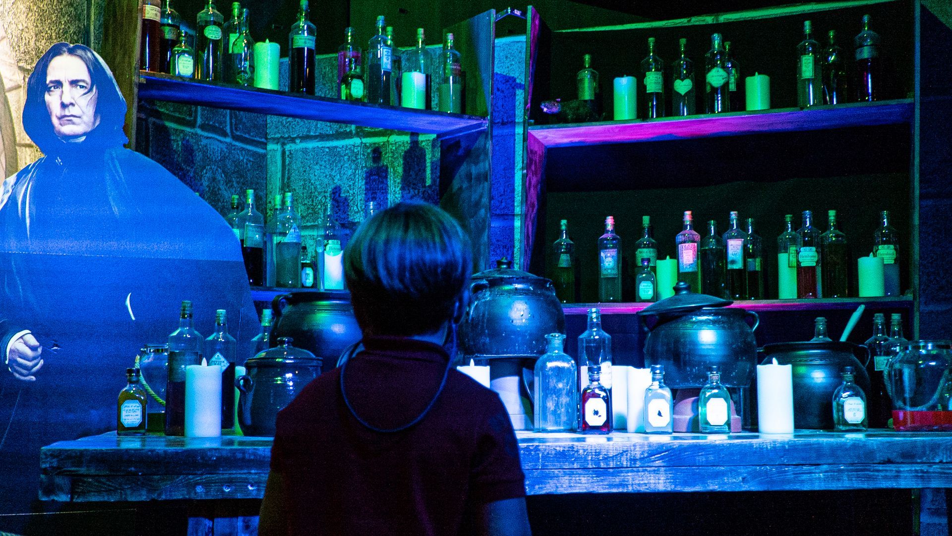 Una persona está parada frente a una exhibición de botellas y ollas.